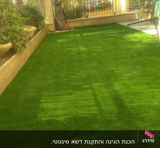 דשא סינתטי עם עציצים תלויים בגינה